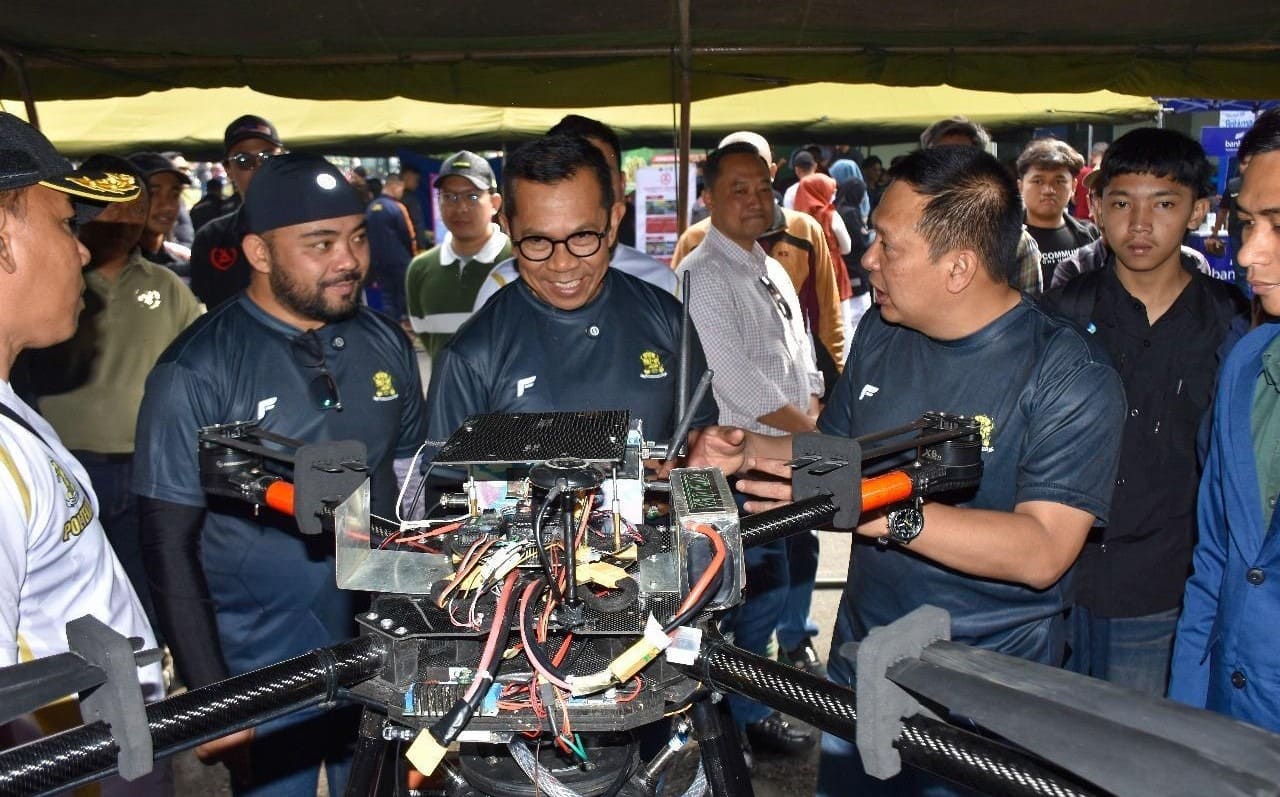 Panggung acara Poltekad Techno Fest 2025 dengan latar pameran teknologi dan komunitas otomotif