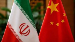 Ilustrasi bendera Iran dan China dengan latar kilang minyak sebagai simbol kerja sama perdagangan energi di tengah ancaman sanksi AS.